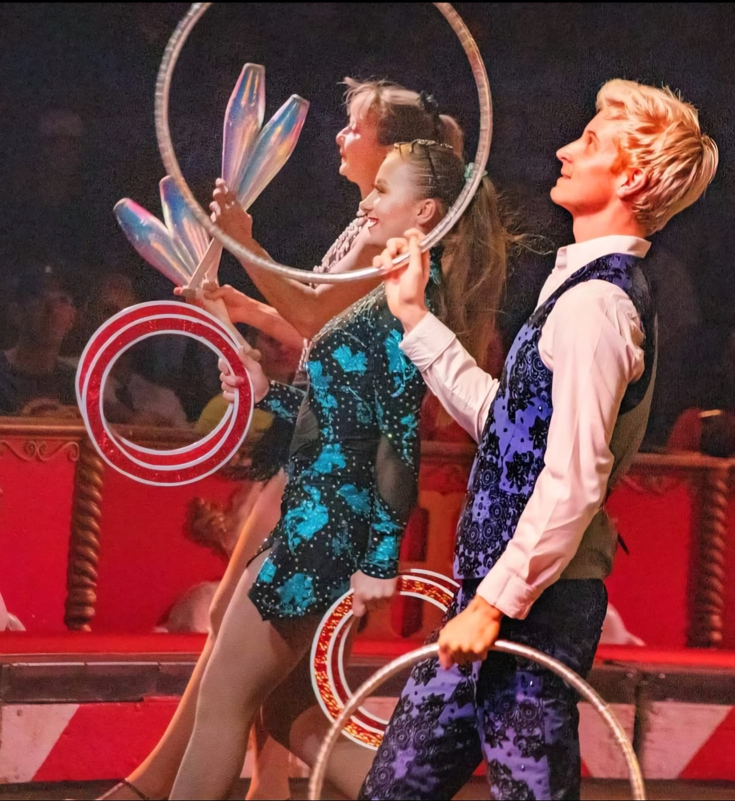Three performers juggling clubs and rings