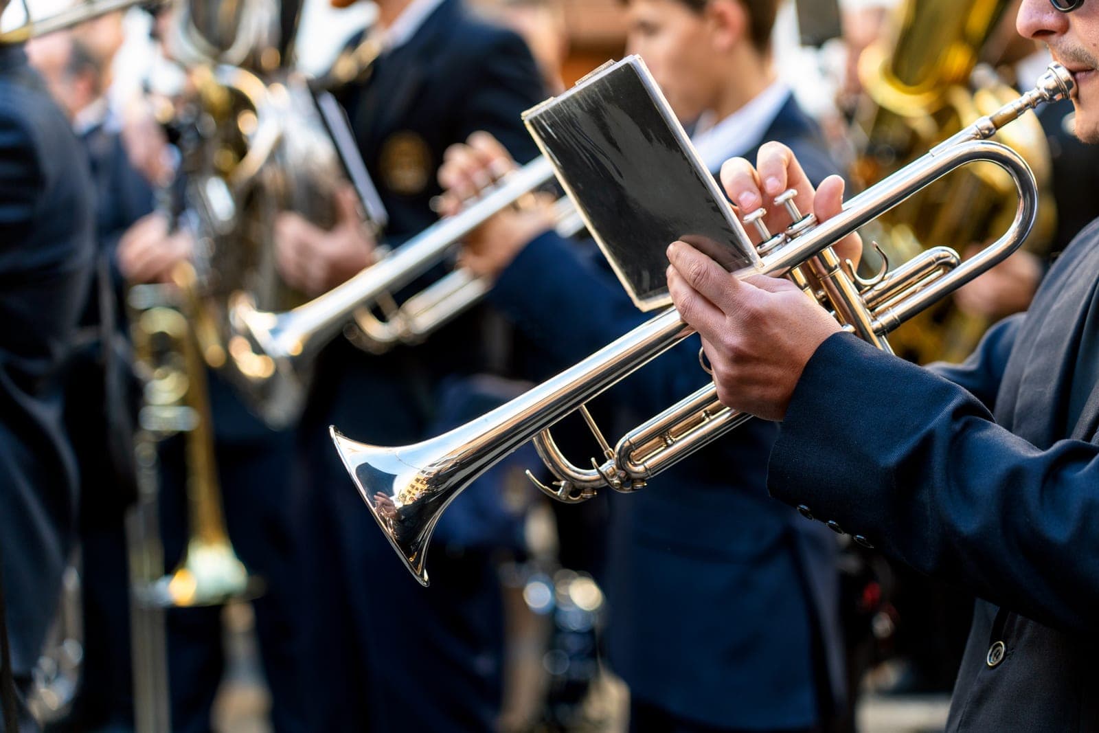 Brass players in navy uniforms mid-performance, trumpets raised
